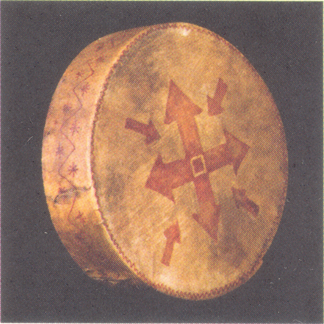 Image of a small and relatively flatcylindrical drum / sacred cultural object with an inscription of an arrowed cross on it in red. Scanned in from the Berber museum catalogue.