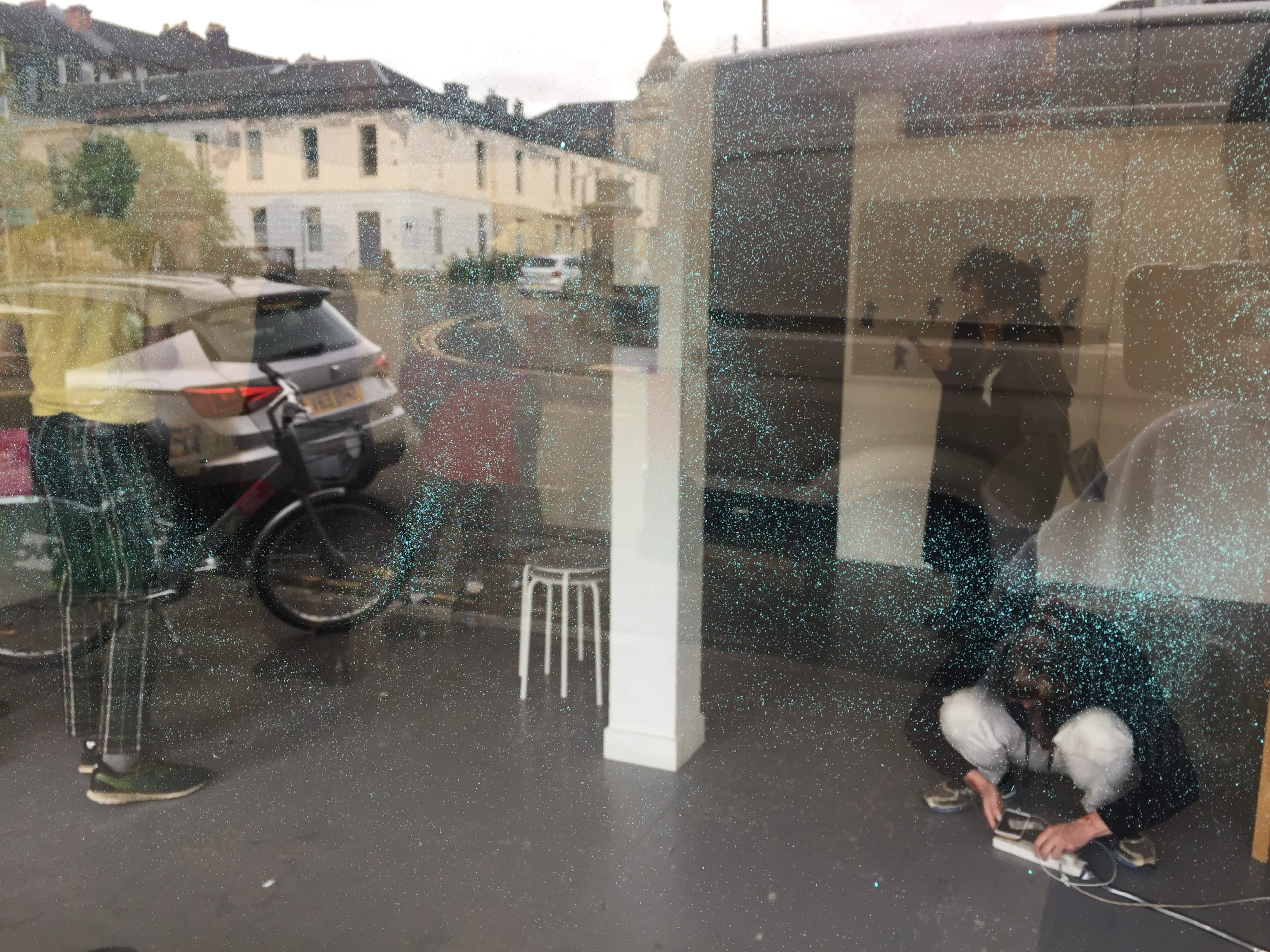 looking through window with spray paint into an event happening at Market Gallery