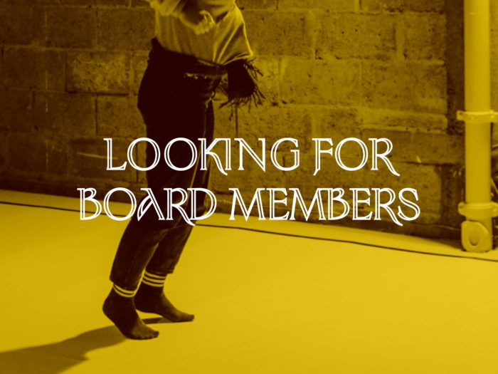 A yellow tinted image of a person jumping wearing jeans and black socks in a gallery space, over the image the text reads "looking for board members"