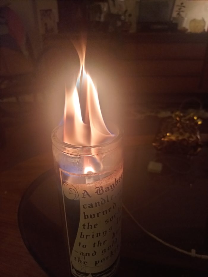 A close up of a bayber candle on a tall glass container with text written on it. 