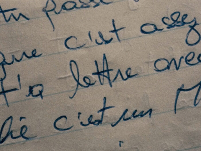 A very close up image of a paper with a handwritten text on blue pen.