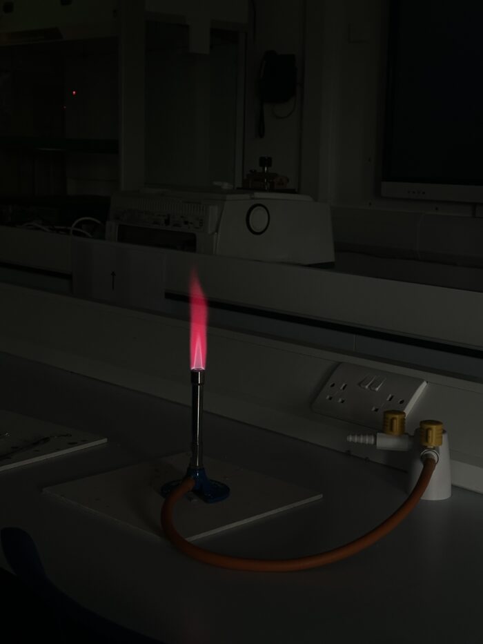 A bunsen burner with a red flame on a lab room