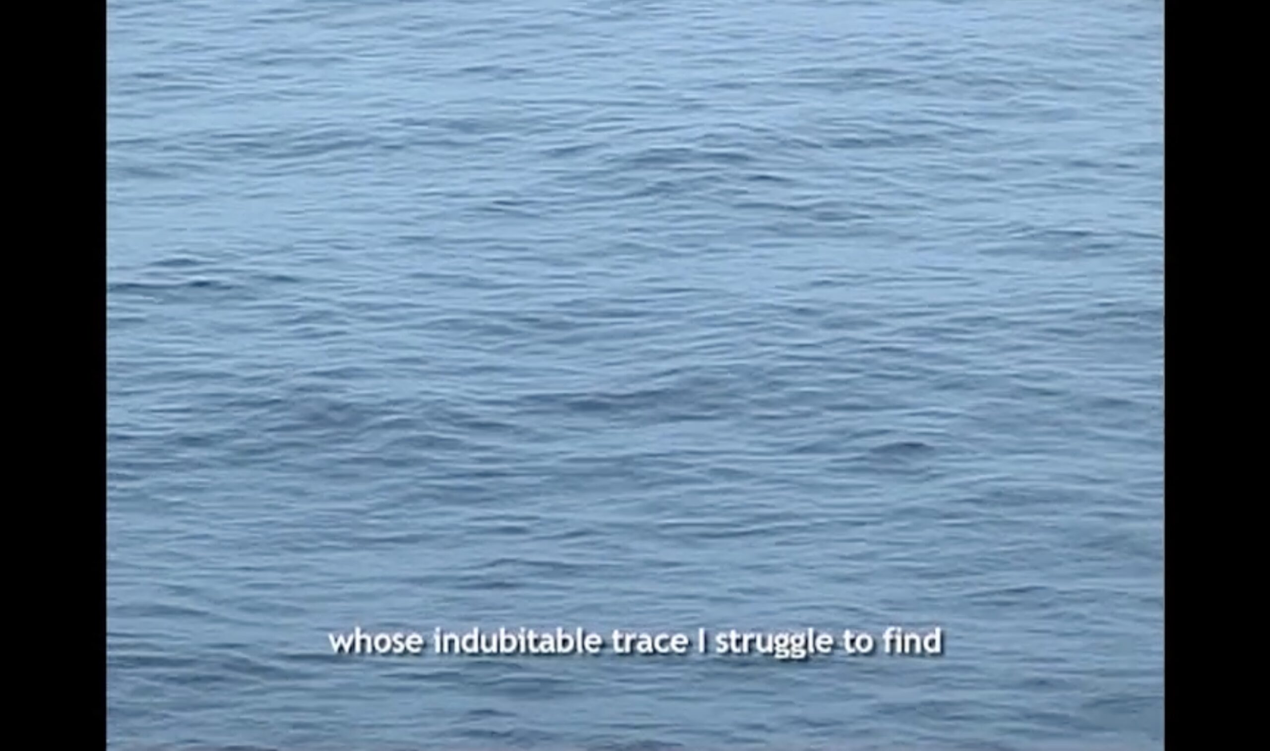 Film still showing an image of gentle ocean waves filling the entire shot, with a caption in white writing reading: "whose indubitable trace I struggle to find" Image: Film still from 'Édouard Glissant: One World in Relation' (trailer) Manthia Diawara, 2010.