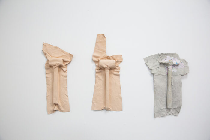 Three relief casts of hammers in textile are on a blank surface. 