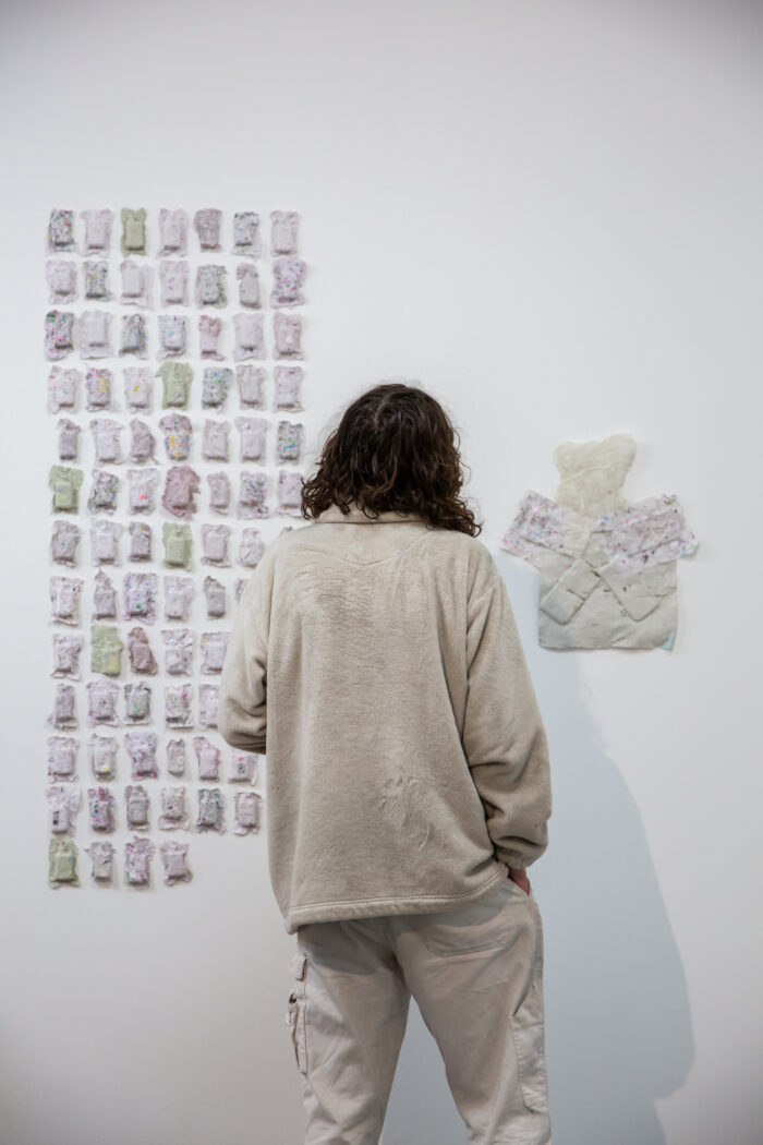 The back of a person looking at two works on the wall. 