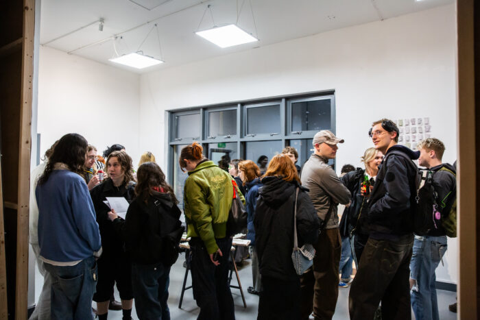 a crowd of people in a gallery space, chatting and looking at the room